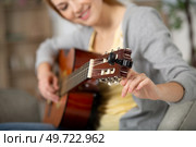 musical tutor woman tunes guitar while sitting on sofa. Стоковое фото, агентство Ingram Publishing / Фотобанк Лори
