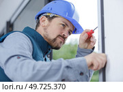 a man builder fixes a window. Стоковое фото, агентство Ingram Publishing / Фотобанк Лори