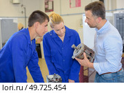 Apprentices looking at electric motor. Стоковое фото, агентство Ingram Publishing / Фотобанк Лори