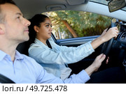 driving school instructor guiding steering wheel for female learner. Стоковое фото, агентство Ingram Publishing / Фотобанк Лори