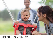 mom swinging baby girl in swing. Стоковое фото, агентство Ingram Publishing / Фотобанк Лори