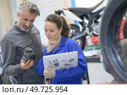 motorcycle mechanics looking at carburetor. Стоковое фото, агентство Ingram Publishing / Фотобанк Лори