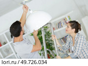 couple installing a lamp in their new home. Стоковое фото, агентство Ingram Publishing / Фотобанк Лори