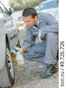 Mechanic spraying car from plastic bottle. Стоковое фото, агентство Ingram Publishing / Фотобанк Лори