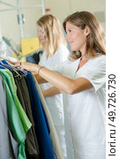 women sorting clothes on rail in professional launderette. Стоковое фото, агентство Ingram Publishing / Фотобанк Лори