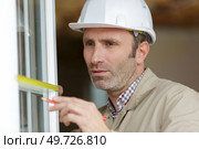 man measuring window prior to installation of roller shutter outdoors. Стоковое фото, агентство Ingram Publishing / Фотобанк Лори