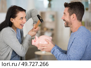 happy couple breaking piggy bank with hammer at home. Стоковое фото, агентство Ingram Publishing / Фотобанк Лори