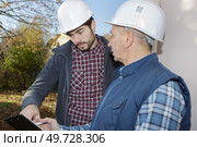Workmen wearing hardhats in discussion. Стоковое фото, агентство Ingram Publishing / Фотобанк Лори