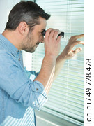 man looking through binoculars at window blind. Стоковое фото, агентство Ingram Publishing / Фотобанк Лори