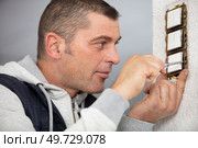man installing electrical outlet checking the fastening of the screws. Стоковое фото, агентство Ingram Publishing / Фотобанк Лори