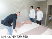 manager is teaching trainees to make bed in room. Стоковое фото, агентство Ingram Publishing / Фотобанк Лори