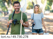 happy couple walking with rods going from fishing. Стоковое фото, агентство Ingram Publishing / Фотобанк Лори