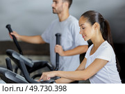 gym clients using elliptical walker trainer machine. Стоковое фото, агентство Ingram Publishing / Фотобанк Лори