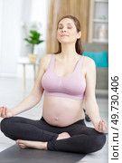 pregnant woman meditating at home practicing yoga. Стоковое фото, агентство Ingram Publishing / Фотобанк Лори
