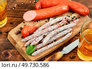 Smoked kabanos sausages, prepared from mixed minced meat with the addition of spices. Salami sticks, sausages and cold beer. Bar or pub.. Kabanos, sausages, Oktoberfest food. Стоковое фото, агентство Ingram Publishing / Фотобанк Лори