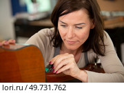 woman luthier is repairing a guitar. Стоковое фото, агентство Ingram Publishing / Фотобанк Лори