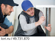 worker carpenter and his apprentice screwing chair leg. Стоковое фото, агентство Ingram Publishing / Фотобанк Лори