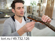 adult artisan fixing old classic guitar. Стоковое фото, агентство Ingram Publishing / Фотобанк Лори