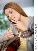 guitarist woman smoking cigarette at home. Стоковое фото, агентство Ingram Publishing / Фотобанк Лори