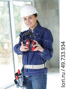 female builder holding ear defenders. Стоковое фото, агентство Ingram Publishing / Фотобанк Лори