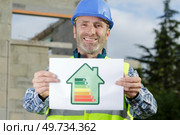 a construction worker holding an energy efficiency rating sign. Стоковое фото, агентство Ingram Publishing / Фотобанк Лори