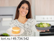 woman holding forwards a burger and a fresh salad. Стоковое фото, агентство Ingram Publishing / Фотобанк Лори
