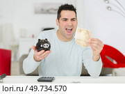 happy man holding saved money. Стоковое фото, агентство Ingram Publishing / Фотобанк Лори