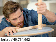 man carpenter with screwdriver in hand working in furniture repair. Стоковое фото, агентство Ingram Publishing / Фотобанк Лори