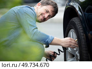 smiling man inflated rubber tires of his car. Стоковое фото, агентство Ingram Publishing / Фотобанк Лори
