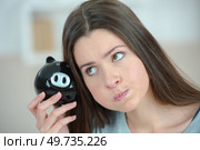 woman looking weird holding a piggy bank. Стоковое фото, агентство Ingram Publishing / Фотобанк Лори