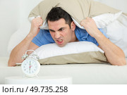 man shouting angrily at alarm clock which has awoken him. Стоковое фото, агентство Ingram Publishing / Фотобанк Лори