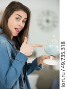 woman winkand and pointing to a globe. Стоковое фото, агентство Ingram Publishing / Фотобанк Лори