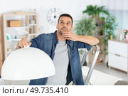 man deciding where to hang new lamp at home. Стоковое фото, агентство Ingram Publishing / Фотобанк Лори