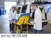 Paramedics wheeling empty stretcher to vehicle. Стоковое фото, агентство Ingram Publishing / Фотобанк Лори