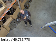 Warehouse worker looking up into racking. Стоковое фото, агентство Ingram Publishing / Фотобанк Лори
