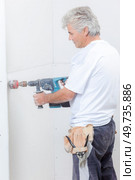 Builder using drill with attachment to make hole. Стоковое фото, агентство Ingram Publishing / Фотобанк Лори
