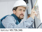 man measuring window prior to installation of roller shutter outdoors. Стоковое фото, агентство Ingram Publishing / Фотобанк Лори