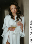 brown-haired girl in the morning in a bathrobe in the hotel corridor with a glass of white wine. Стоковое фото, агентство Ingram Publishing / Фотобанк Лори