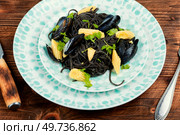 Black bean pasta with boiled mussels or clams. Mediterranean pasta vongole on rustic wooden background.. Black spaghetti pasta linguine with clams. Стоковое фото, агентство Ingram Publishing / Фотобанк Лори