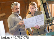 colleagues stood by band saw looking at design drawings. Стоковое фото, агентство Ingram Publishing / Фотобанк Лори