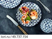 Puff pastry tartlets or canapes with fish, shrimp and bacon on a plate on the table.. Tartlets with seafood and bacon, tasty snack. Стоковое фото, агентство Ingram Publishing / Фотобанк Лори