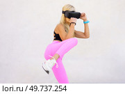 Young blond haired female athlete in sportswear and VR goggles practicing punches and kicks during virtual boxing training against white background. Female boxer in VR headset practicing punches. Стоковое фото, агентство Ingram Publishing / Фотобанк Лори