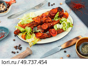 Stewed, roasted pork ribs with tomato sauce in white plate. BBQ.. Tasty stewed pork ribs in sauce. Стоковое фото, агентство Ingram Publishing / Фотобанк Лори