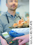 Customer entering code in card machine paying for seafood platter. Стоковое фото, агентство Ingram Publishing / Фотобанк Лори