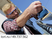 a man sanding outdoor handrail. Стоковое фото, агентство Ingram Publishing / Фотобанк Лори