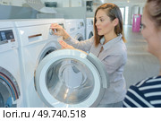 Woman demonstrating washing machine to customer. Стоковое фото, агентство Ingram Publishing / Фотобанк Лори