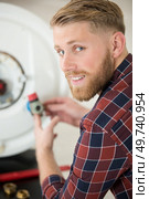 a professional electrician man is fixing a water heater. Стоковое фото, агентство Ingram Publishing / Фотобанк Лори