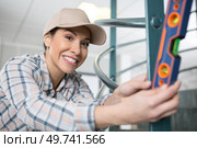 smiling handywoman using spirit level. Стоковое фото, агентство Ingram Publishing / Фотобанк Лори