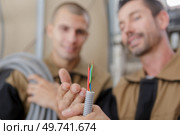 builders looking at the cables coming out of grey trunking. Стоковое фото, агентство Ingram Publishing / Фотобанк Лори