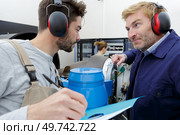 workers wearing earmuffs having conversation. Стоковое фото, агентство Ingram Publishing / Фотобанк Лори